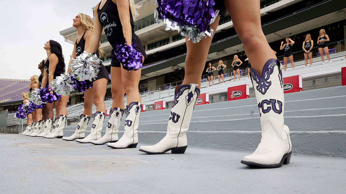 The TCU Showgirls wearing their custom white and purple TCU boots at practice in the stadium stands.